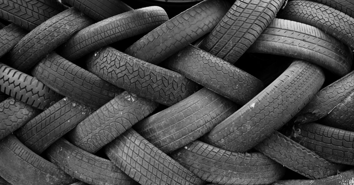 A black and white image showcasing a pile of old rubber tires intricately stacked, creating a textured pattern.